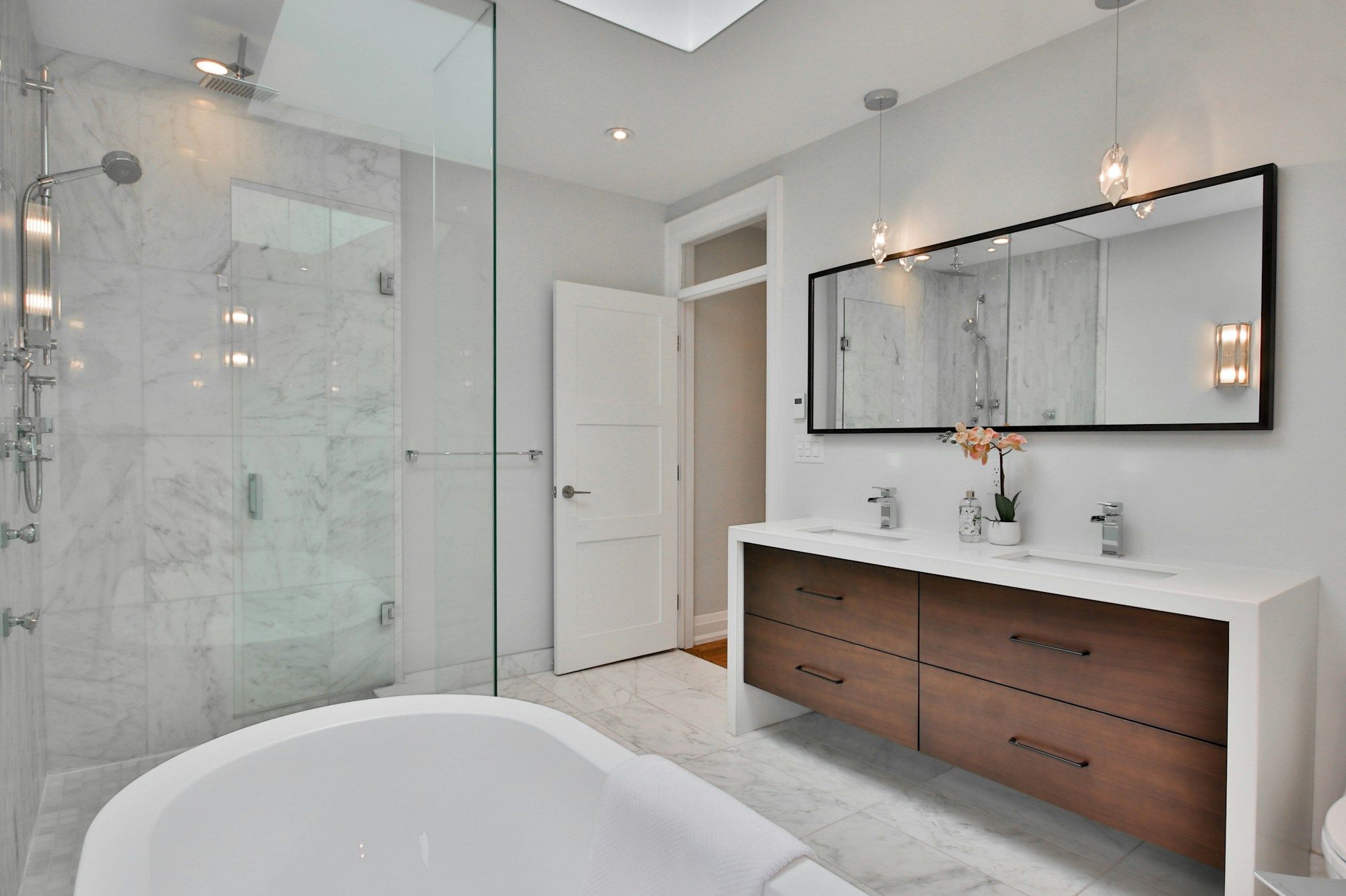 Bright bathroom with a marble floor, a tub and a double vanity
