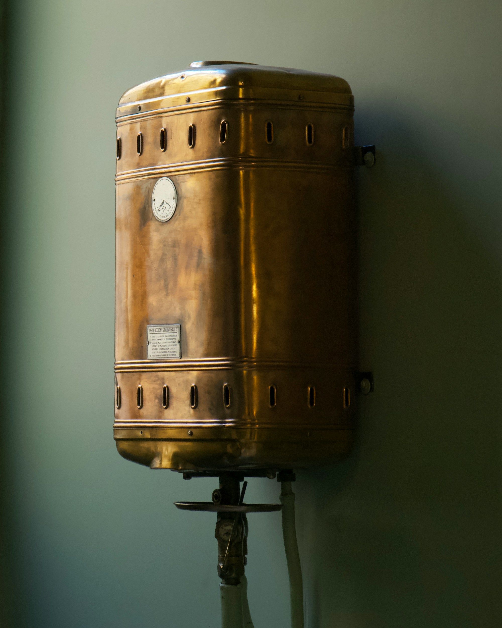 Old copper water tank with a gauge, mounted on a wall