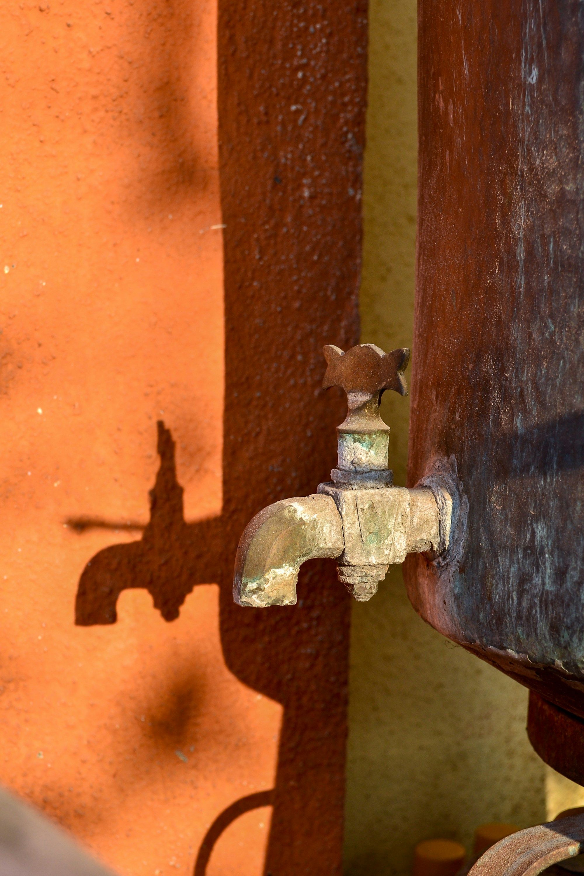 Rusted outdoor water spigot on an orange wall